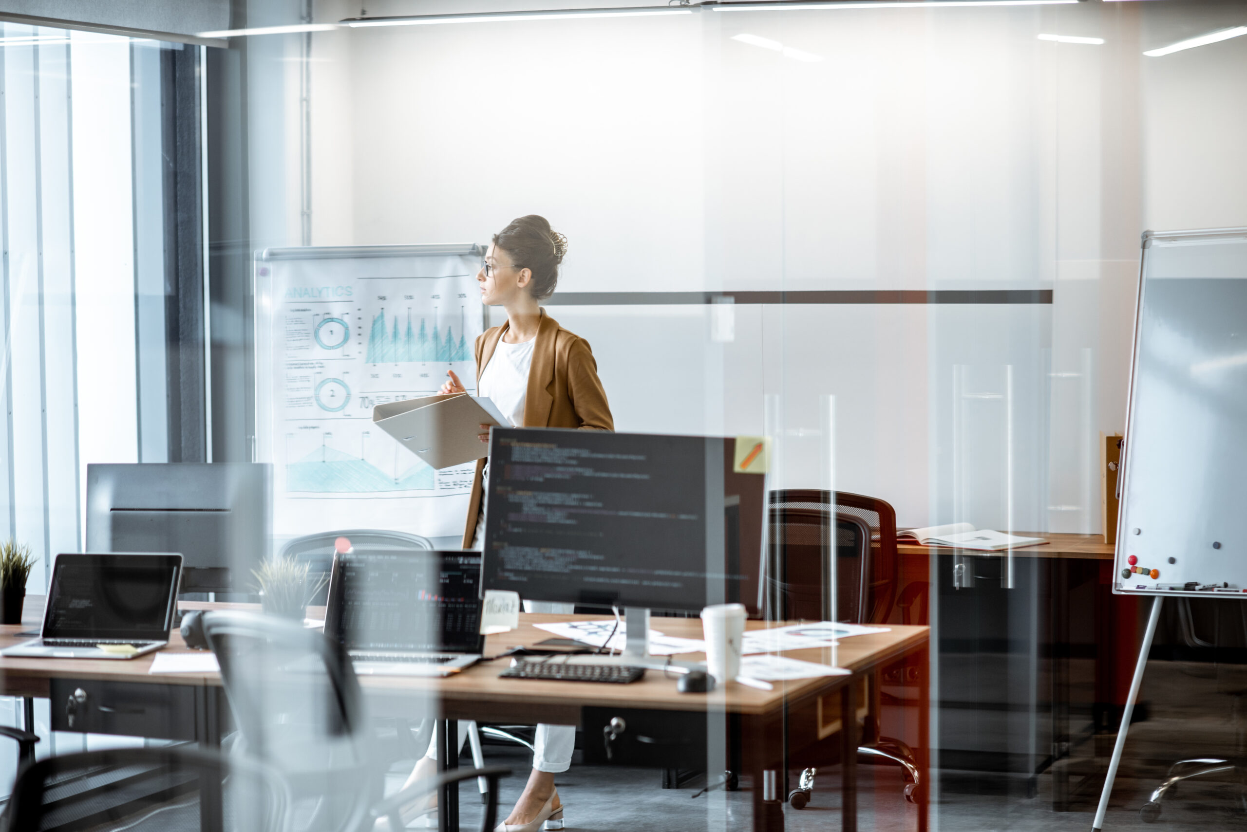 Young business woman preparing for a presentation, standing alone with documents near flipchart in the modern office or coworking space