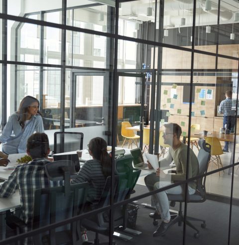 Business meeting. Group of happy smiling multiracial business people discussing project, working together while sitting in a conference room in the modern coworking space. Teamwork, collaboration